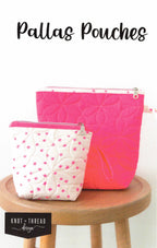 Two quilted pouches, one pink and one white with pink stars, on a wooden stool with 'Knot & Thread Design' branding.