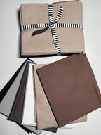 Collection of fabric swatches in neutral colors with a striped ribbon on a white background