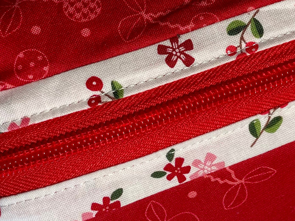 Red and white patterned zippered pouch with a visible brand label on a light gray background