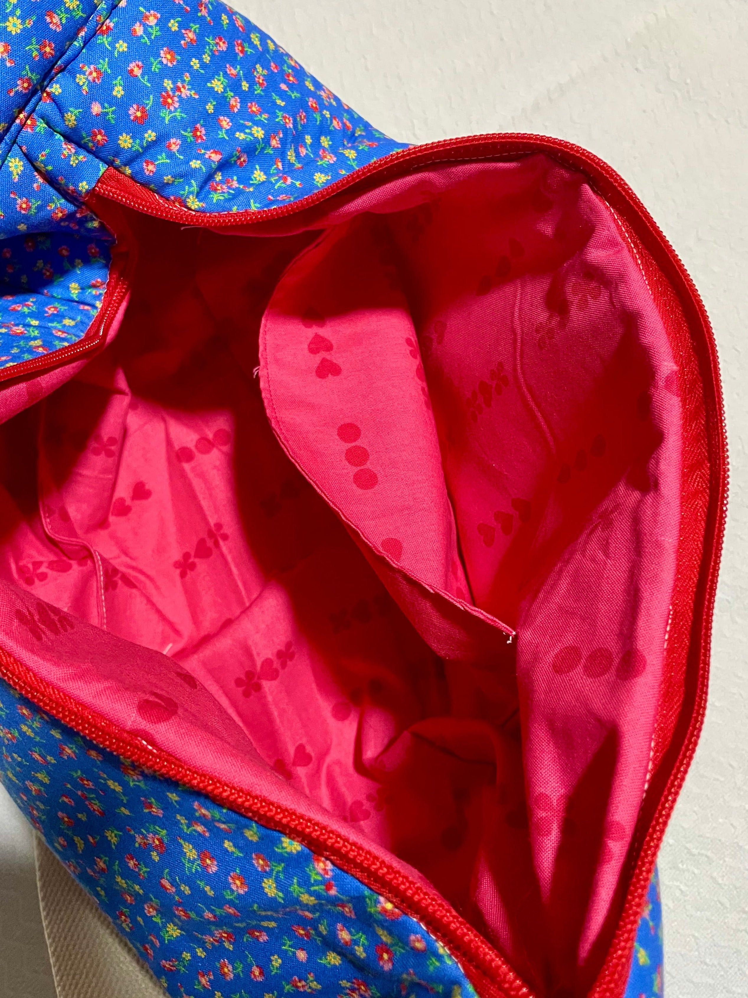 Blue floral-patterned bag with a red interior on a light background