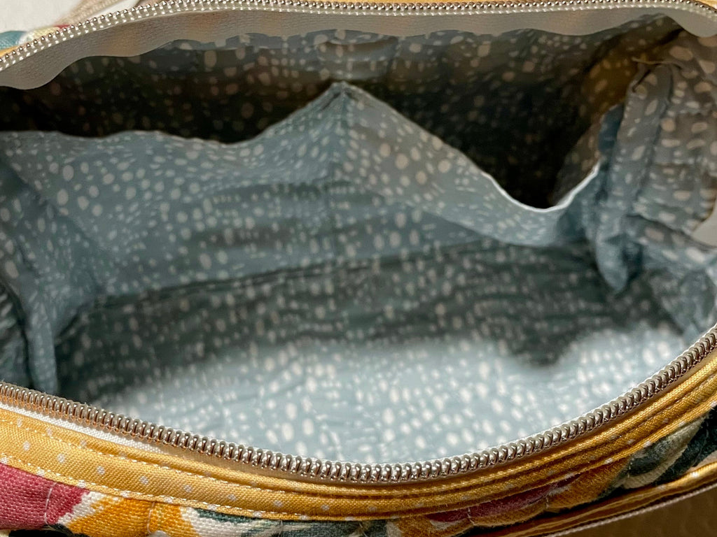 Floral-patterned makeup bag with a visible brand tag on a white background