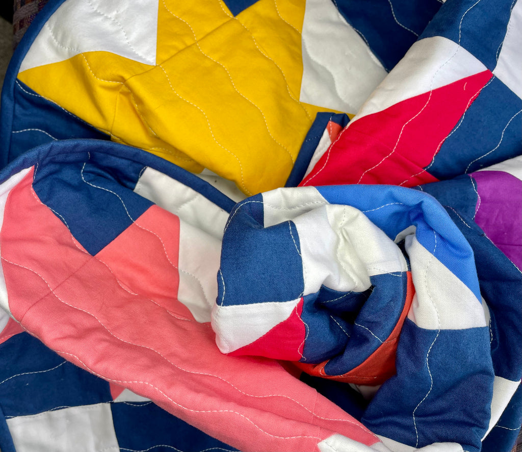 Colorful quilt with star pattern in blue, red, yellow, and white.