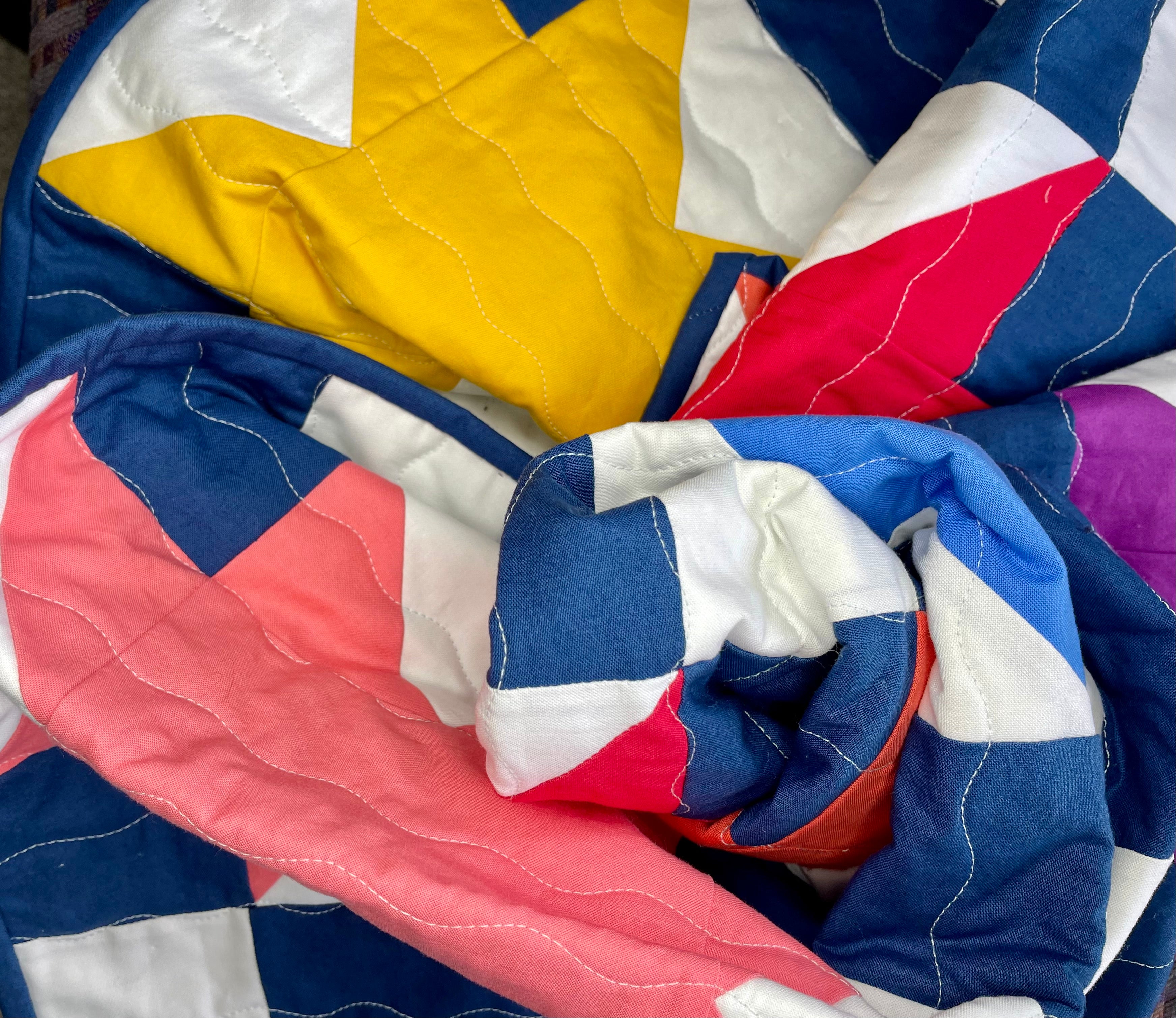 Colorful quilt with star pattern in blue, red, yellow, and white.