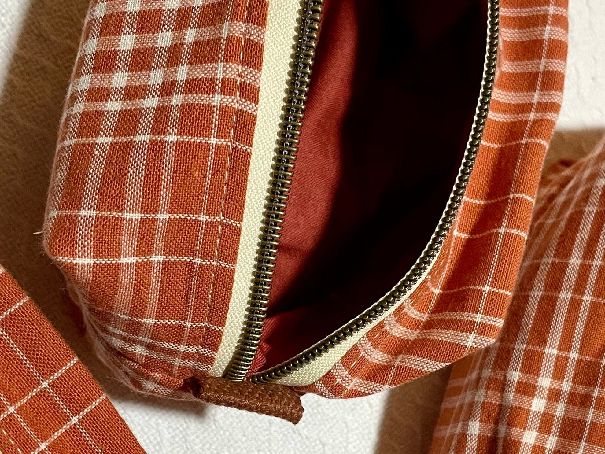 Three plaid pouches with zippers on a white background