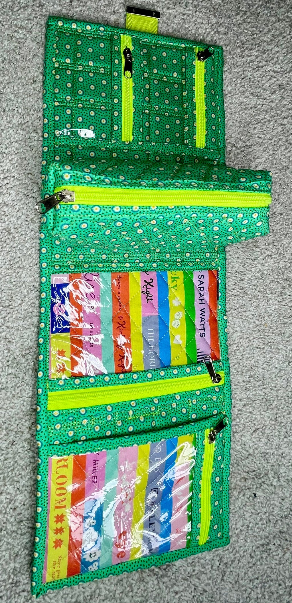 Green fabric wallet with colorful labels on a gray surface