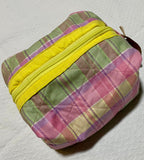Plaid pouch with yellow zipper on a textured white background
