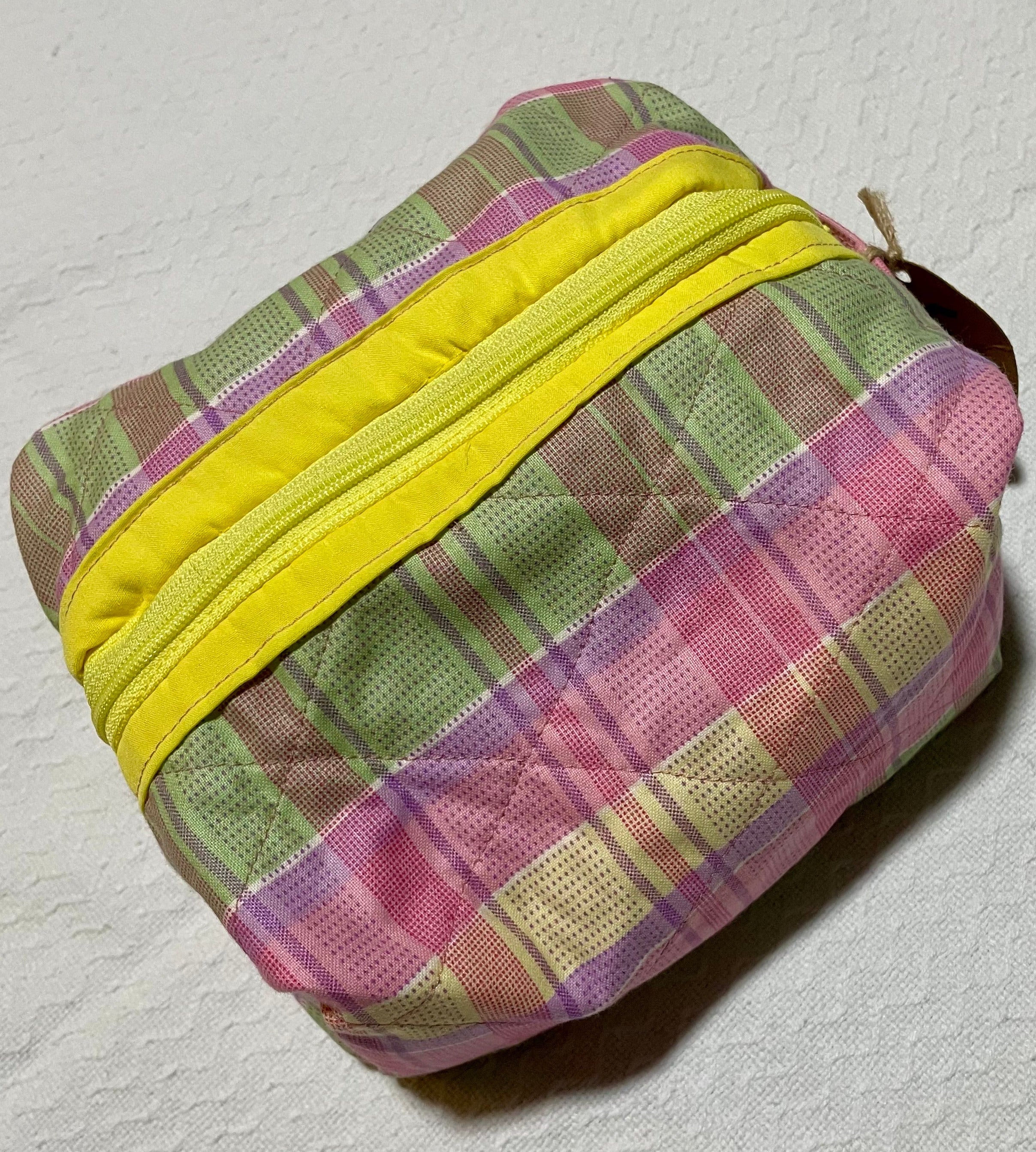Plaid pouch with yellow zipper on a textured white background