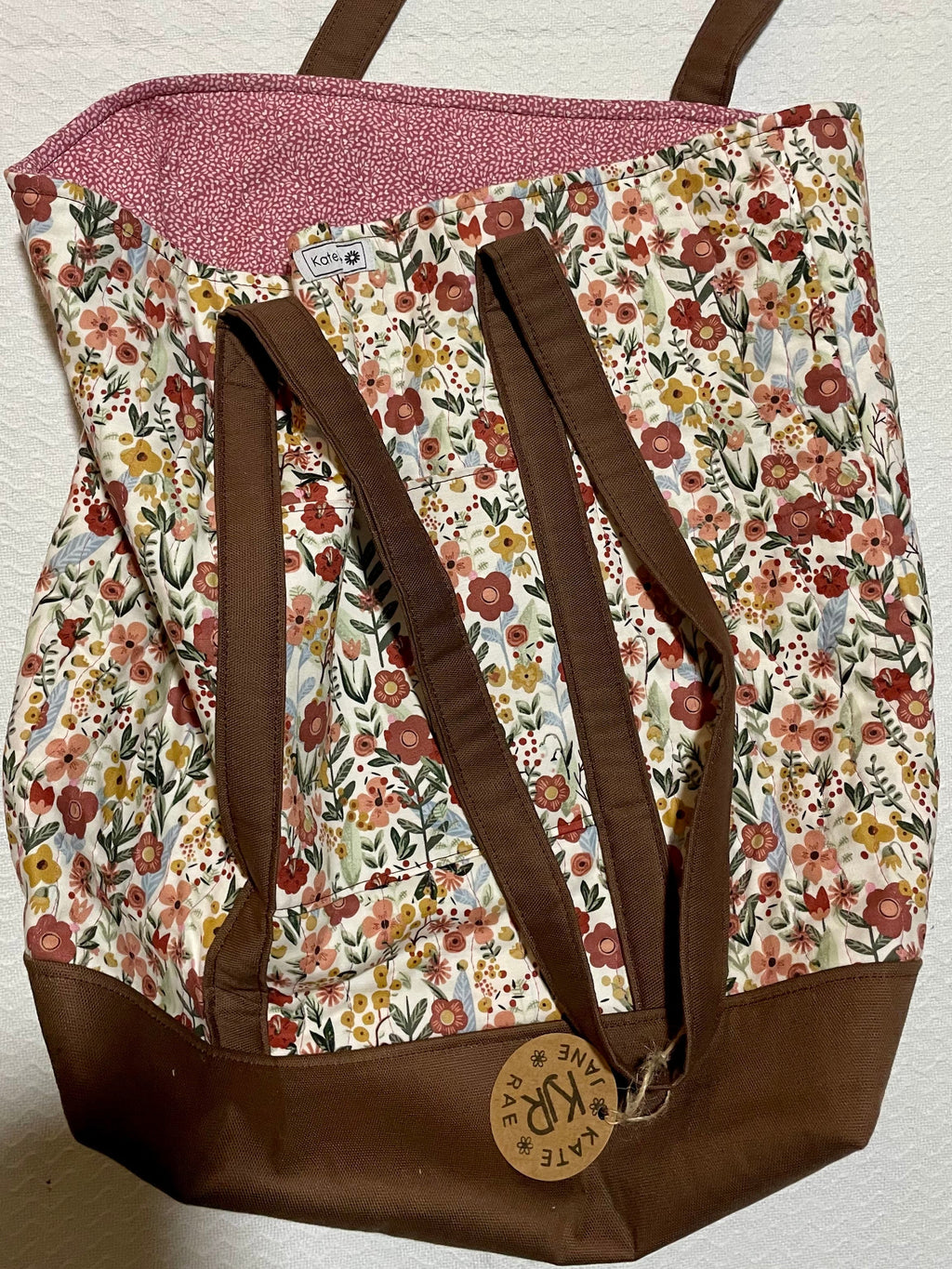 Floral-patterned bag with brown strap on a white background
