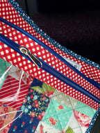 Colorful quilted fabric pouch with a zipper, held open by a hand.