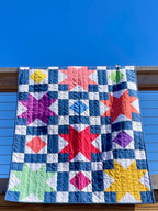Colorful star-patterned quilt against a blue sky