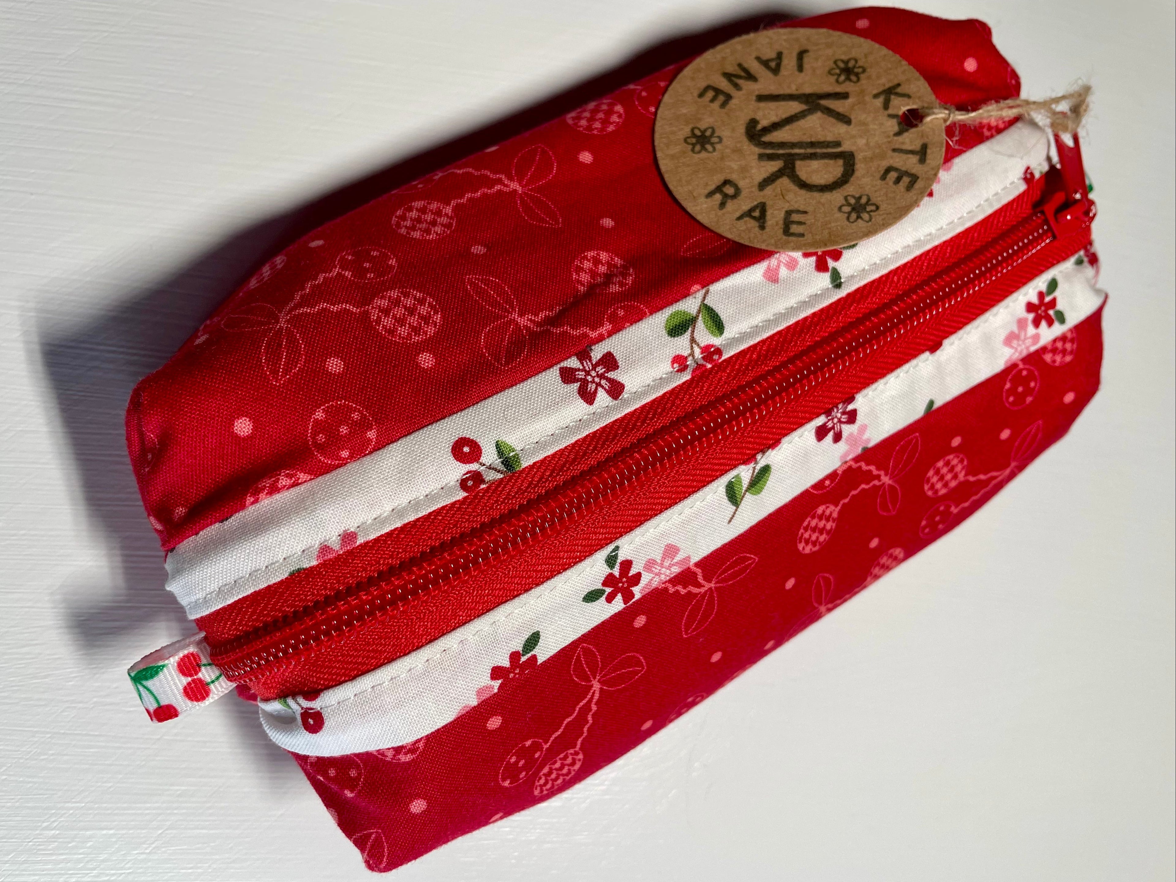 Red and white patterned fabric pouch with a visible brand label on a white background