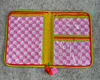 Pink geometric patterned pouch with yellow interior on a gray surface