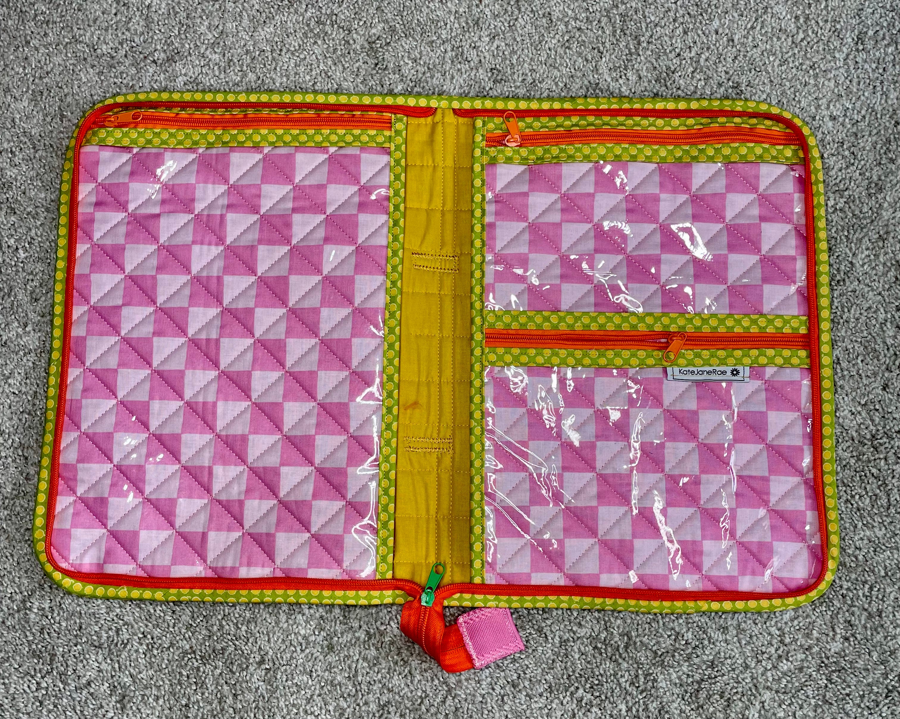 Pink geometric patterned pouch with yellow interior on a gray surface