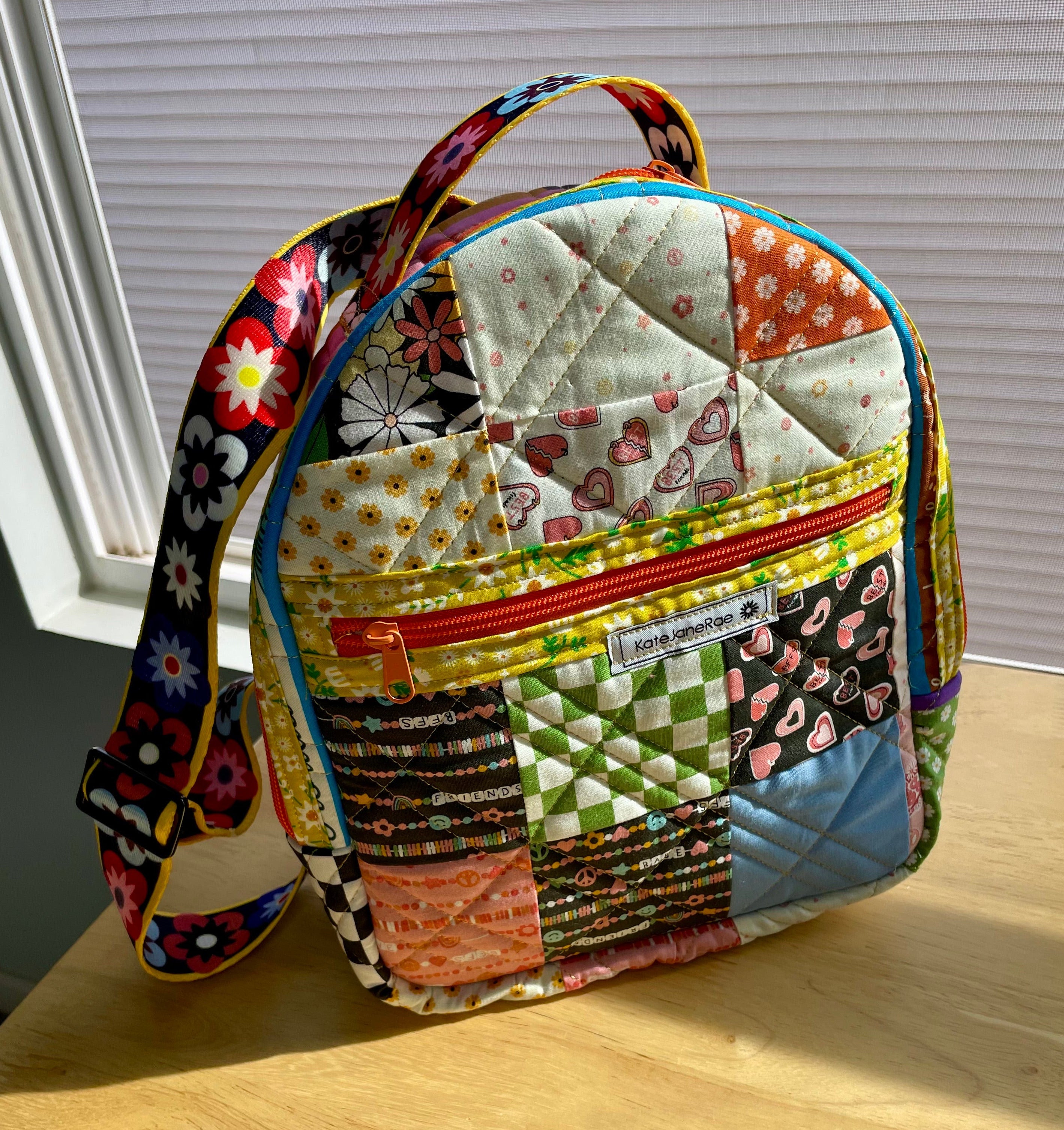 Colorful patchwork backpack on a wooden surface with a window in the background