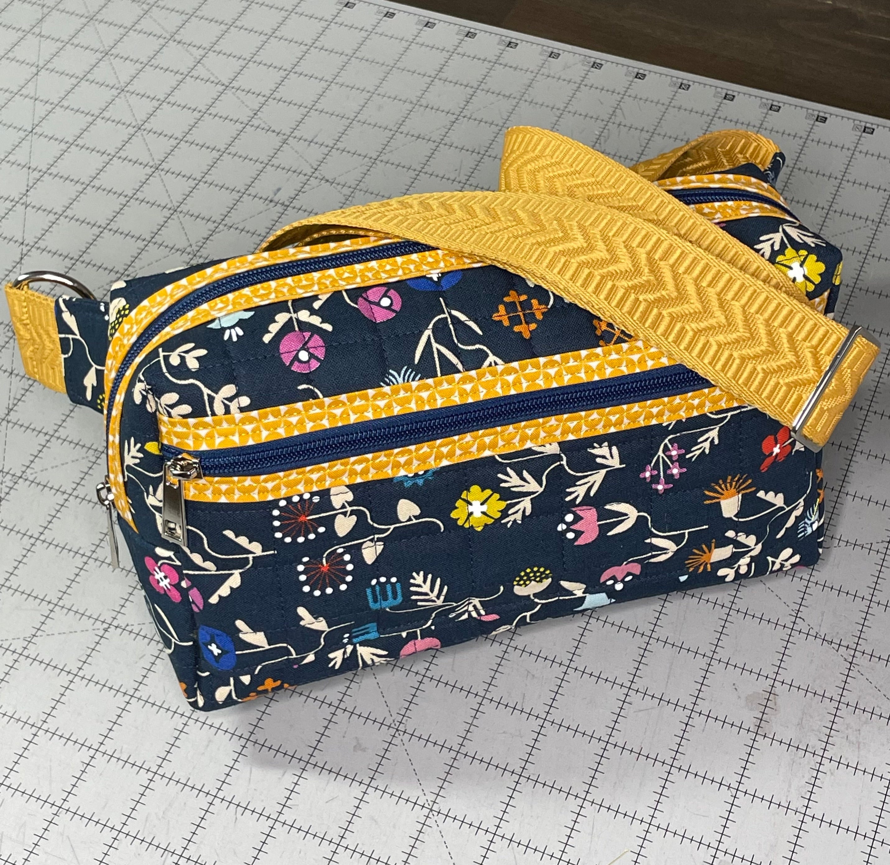 Floral-patterned bag with yellow accents on a grid surface