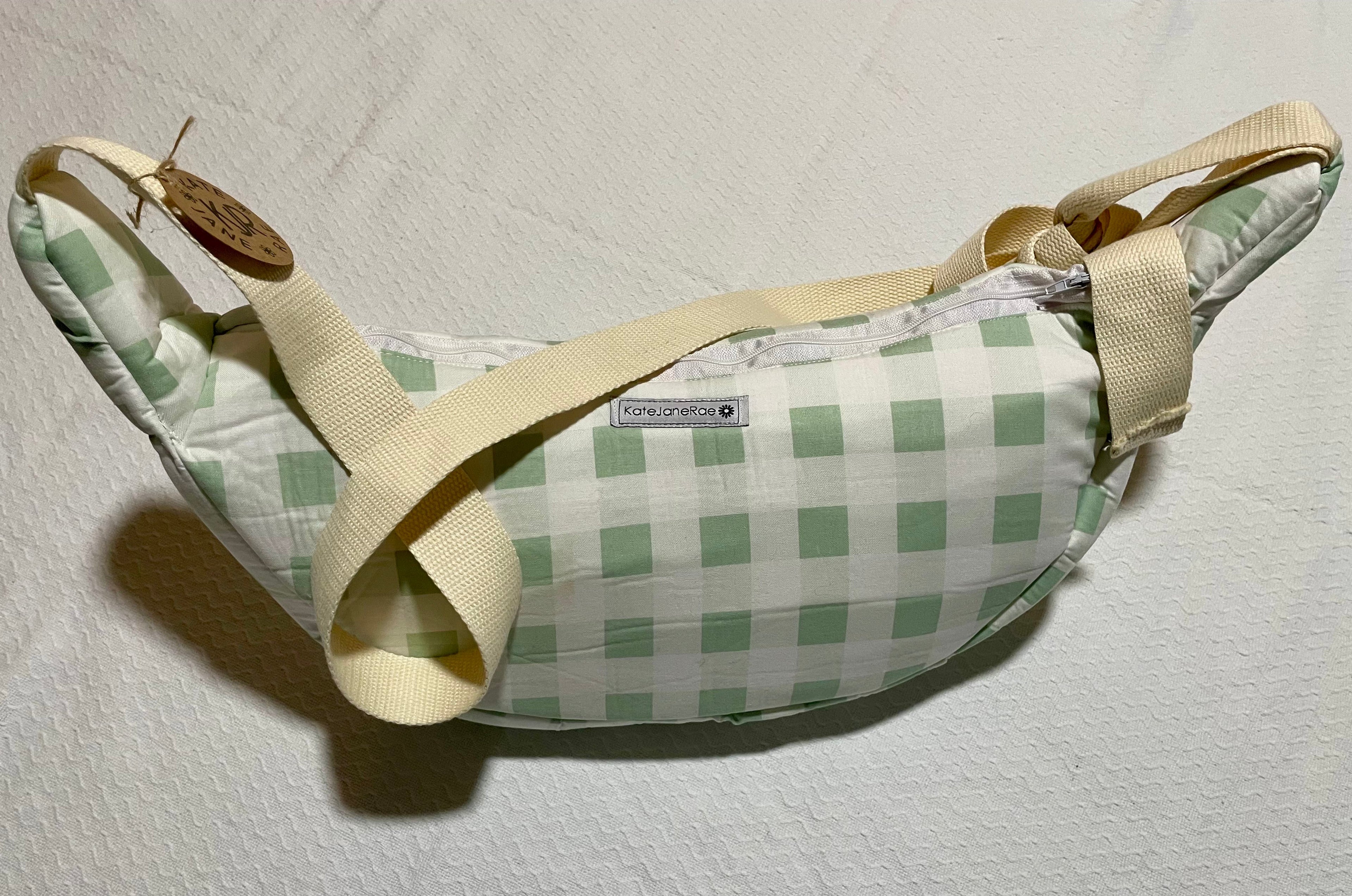 Green checkered bag with beige strap on a light gray background