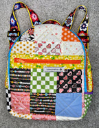 Colorful quilted backpack with floral straps on a gray background