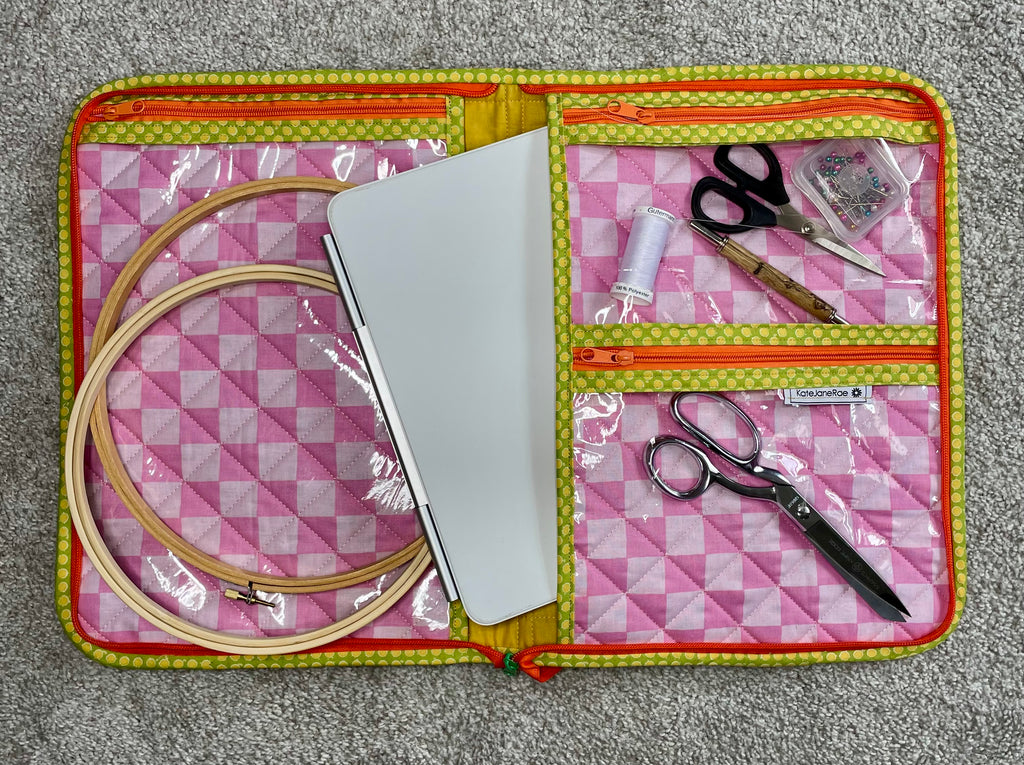 Embroidery kit with hoop, scissors, and other tools in a pink and yellow case.
