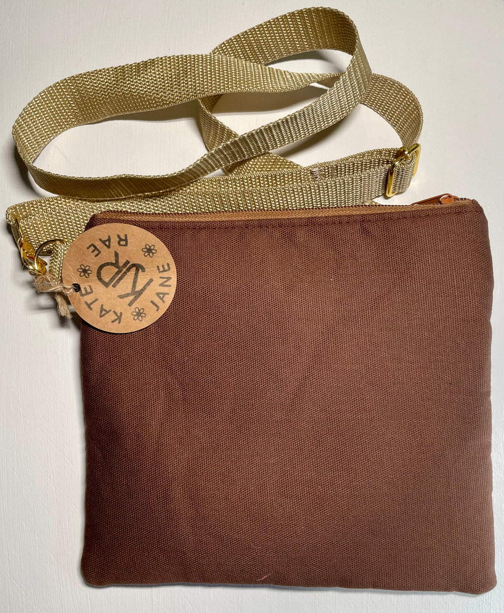 Brown bag with a beige strap and visible brand tag on a white background