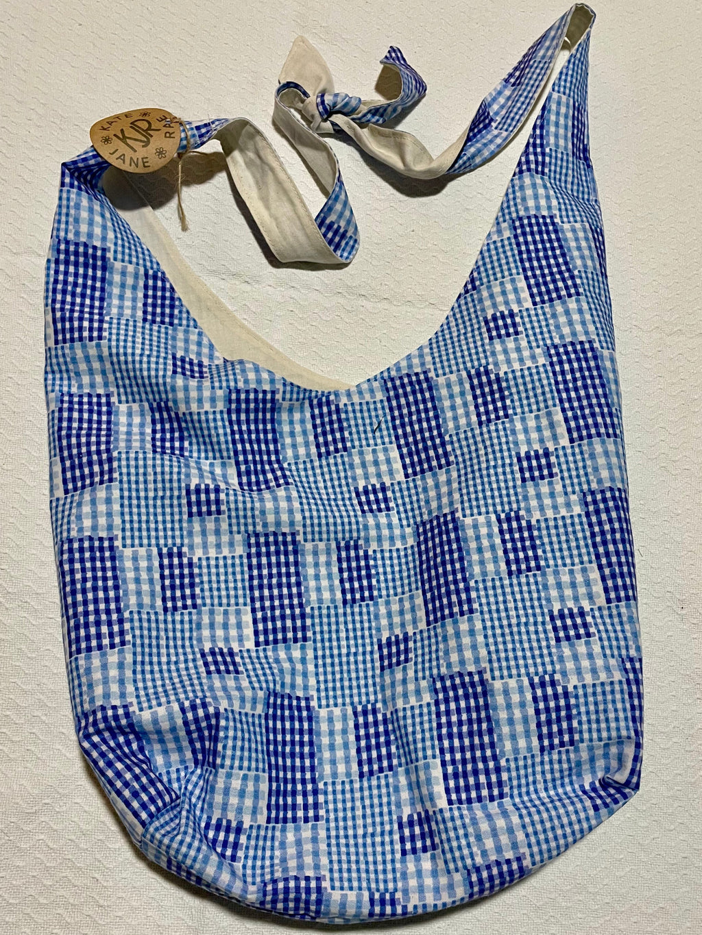 Blue and white checkered sandal with a metal sandal clip on a beige background