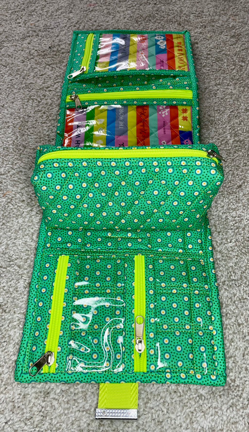 Green polka dot travel wallet with colorful items on a gray surface