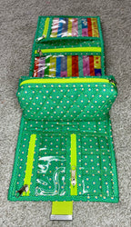 Green polka dot travel wallet with colorful items on a gray surface