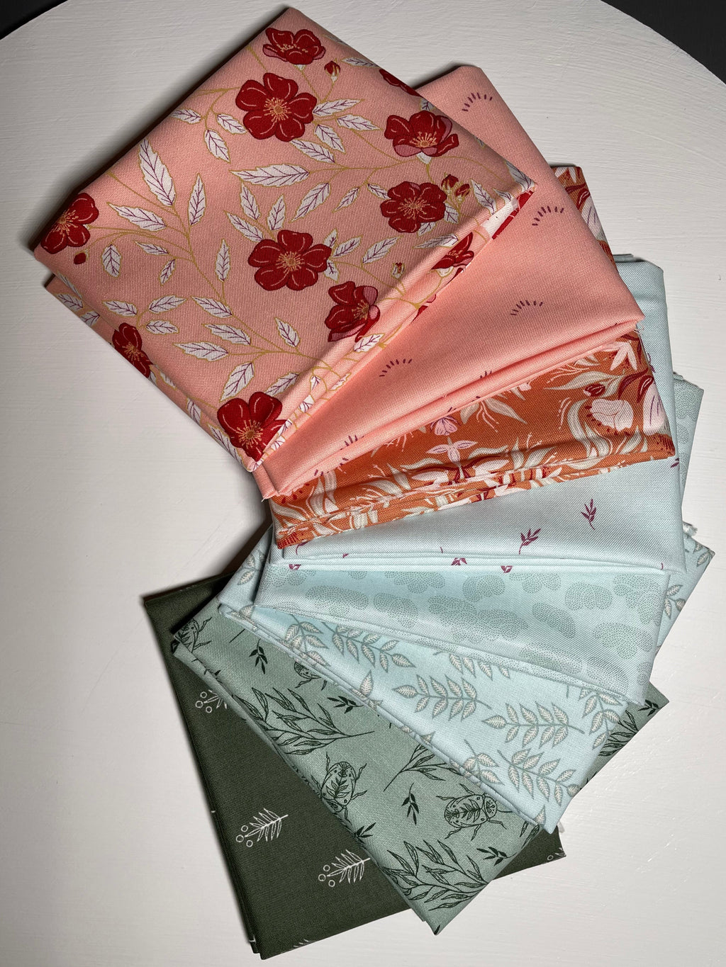 Pink, blue, and green fabric swatches on white table.