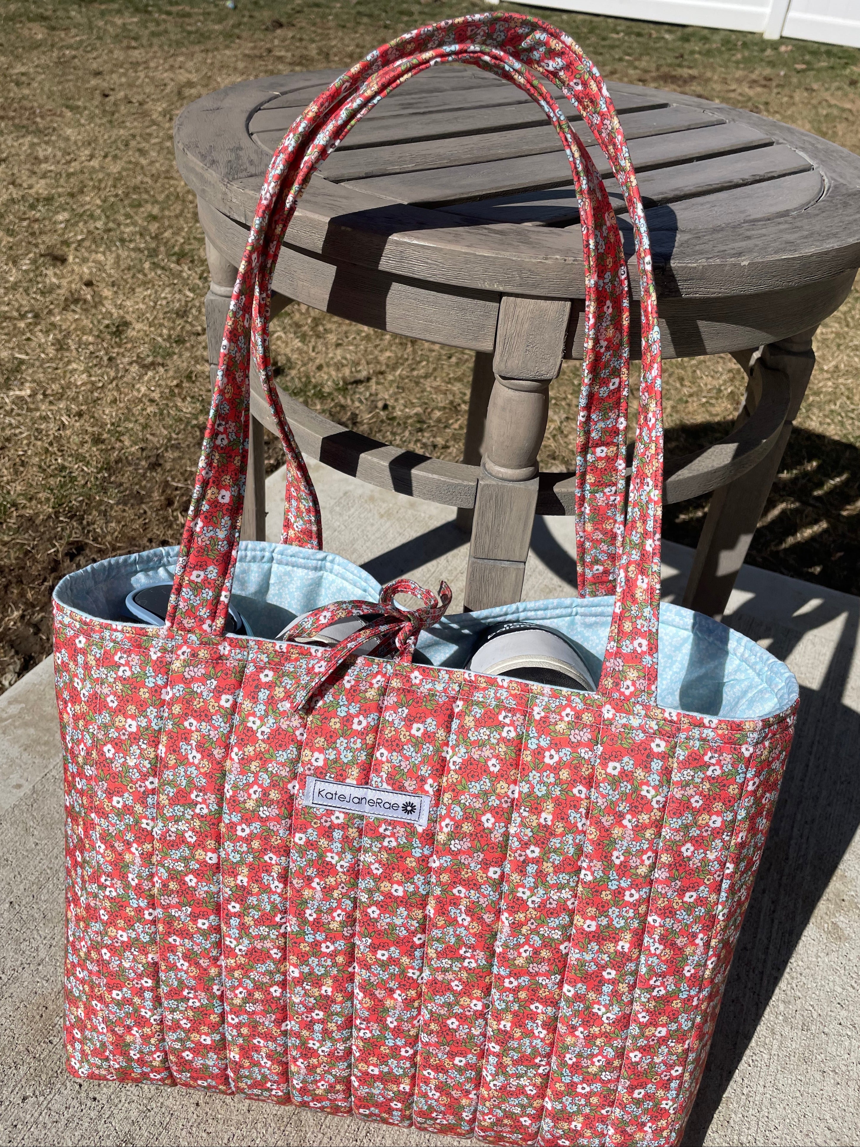 Floral-patterned bag with a visible brand logo on a chair outdoors