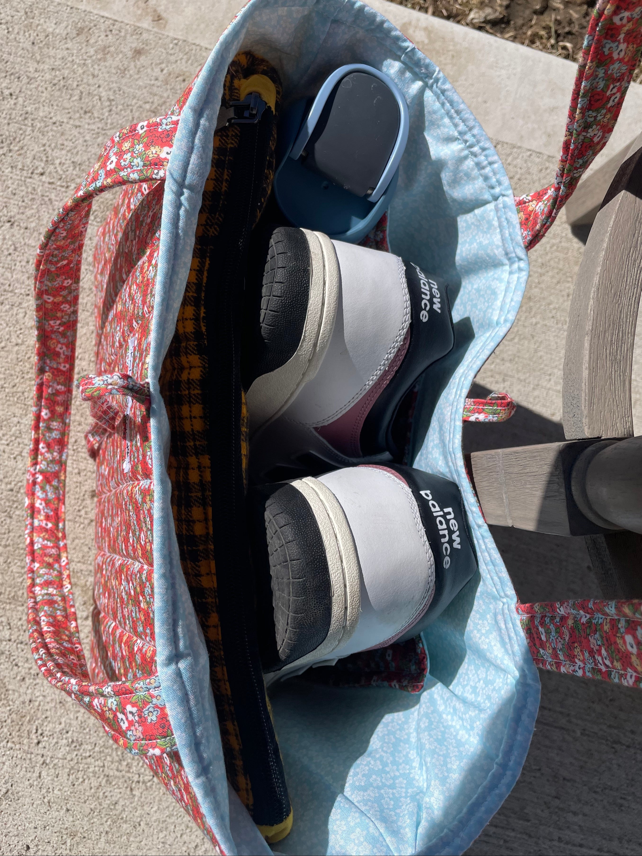 Tote bag with New Balance shoes on a concrete surface