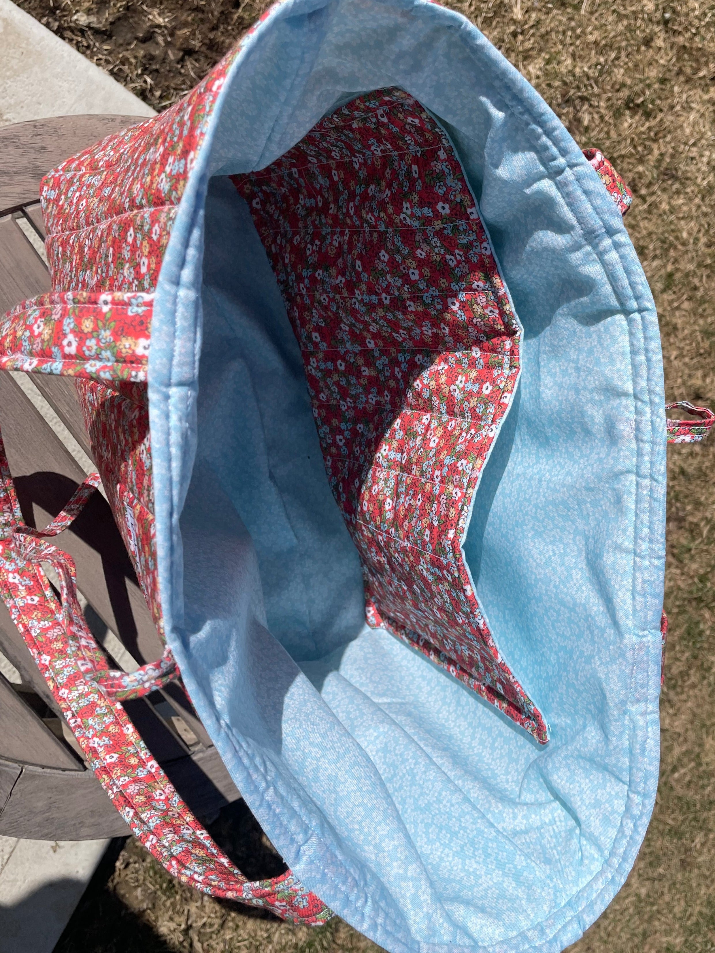 Blue and red patterned bag on a concrete surface with a person's feet in the background.