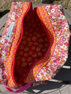Floral-patterned makeup bag with a red interior on a gray surface