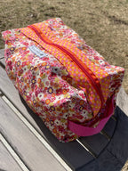 Floral-patterned pouches with pink zippers on a wooden surface.