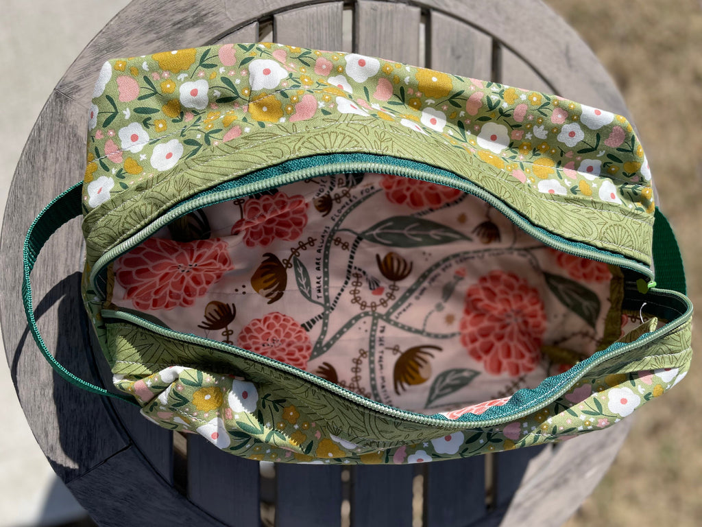 Floral-patterned bag with green trim on a wooden surface