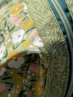 Floral-patterned bag with a green zipper on a wooden surface