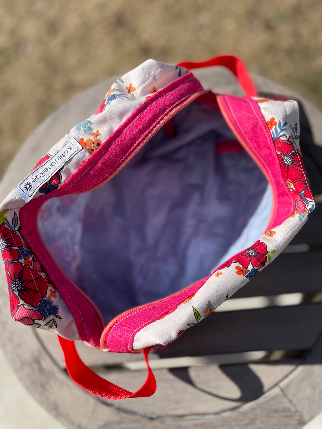 Floral-patterned bag with red straps on a concrete surface