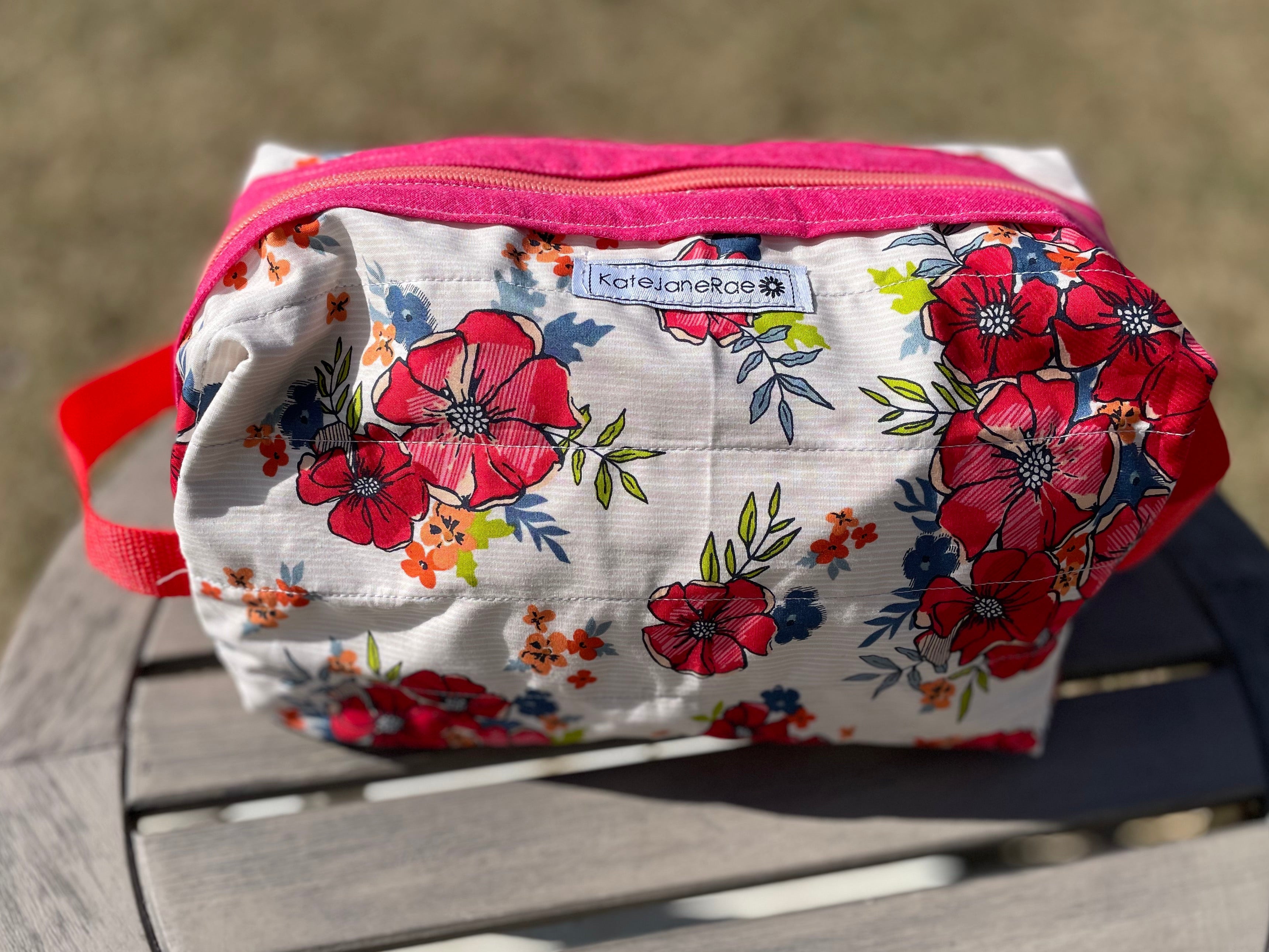 Floral-patterned pouch with a pink zipper on a wooden surface