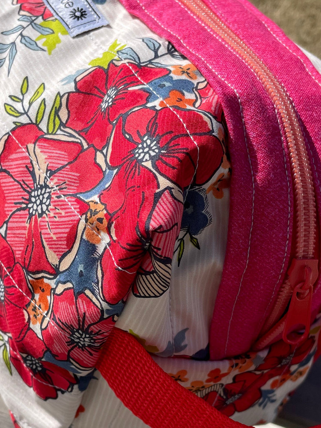 Floral-patterned bag with a pink zipper on a wooden surface