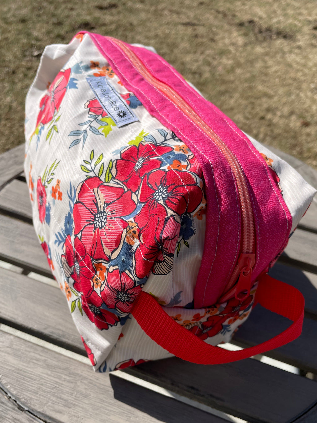 Floral-patterned bag with a pink zipper on a wooden surface