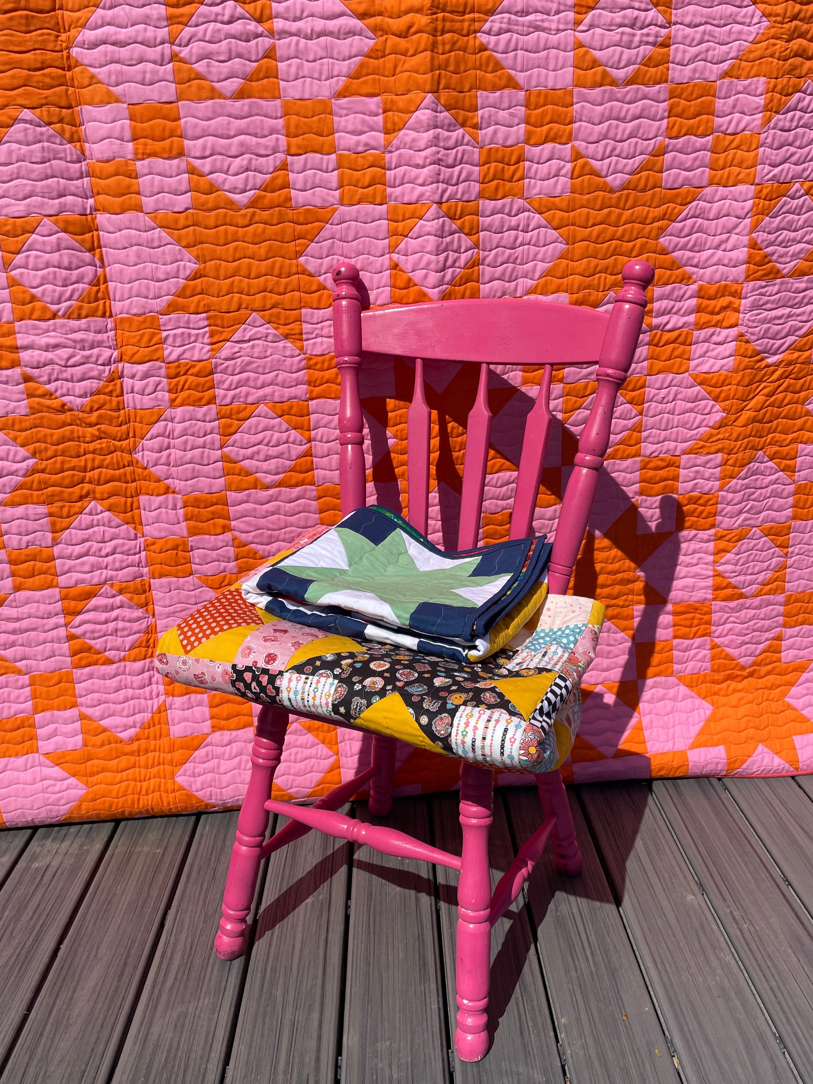 Pink chair with colorful bags on a pink and orange quilt