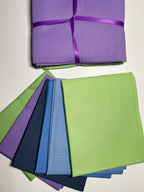 Stack of green, blue, and purple fabric swatches on a white surface