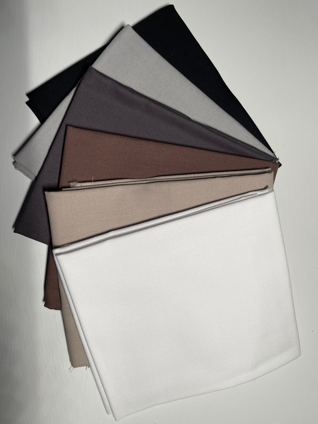 Fabric swatches in black, gray, brown, beige, and white on a light gray background