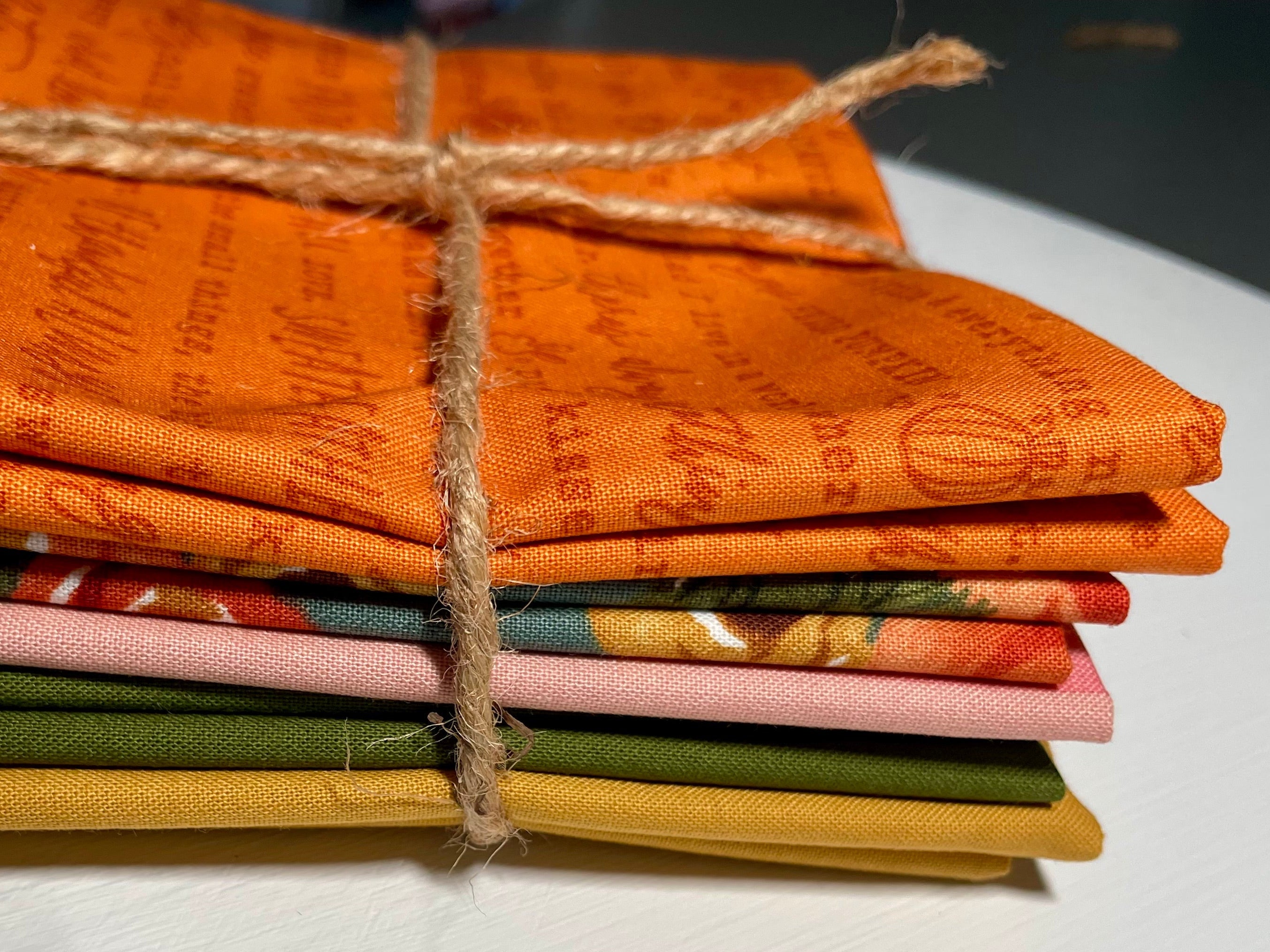 Stack of colorful fabric squares tied with twine on a white surface