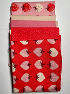 Stack of fabric swatches with strawberry pattern on a white background