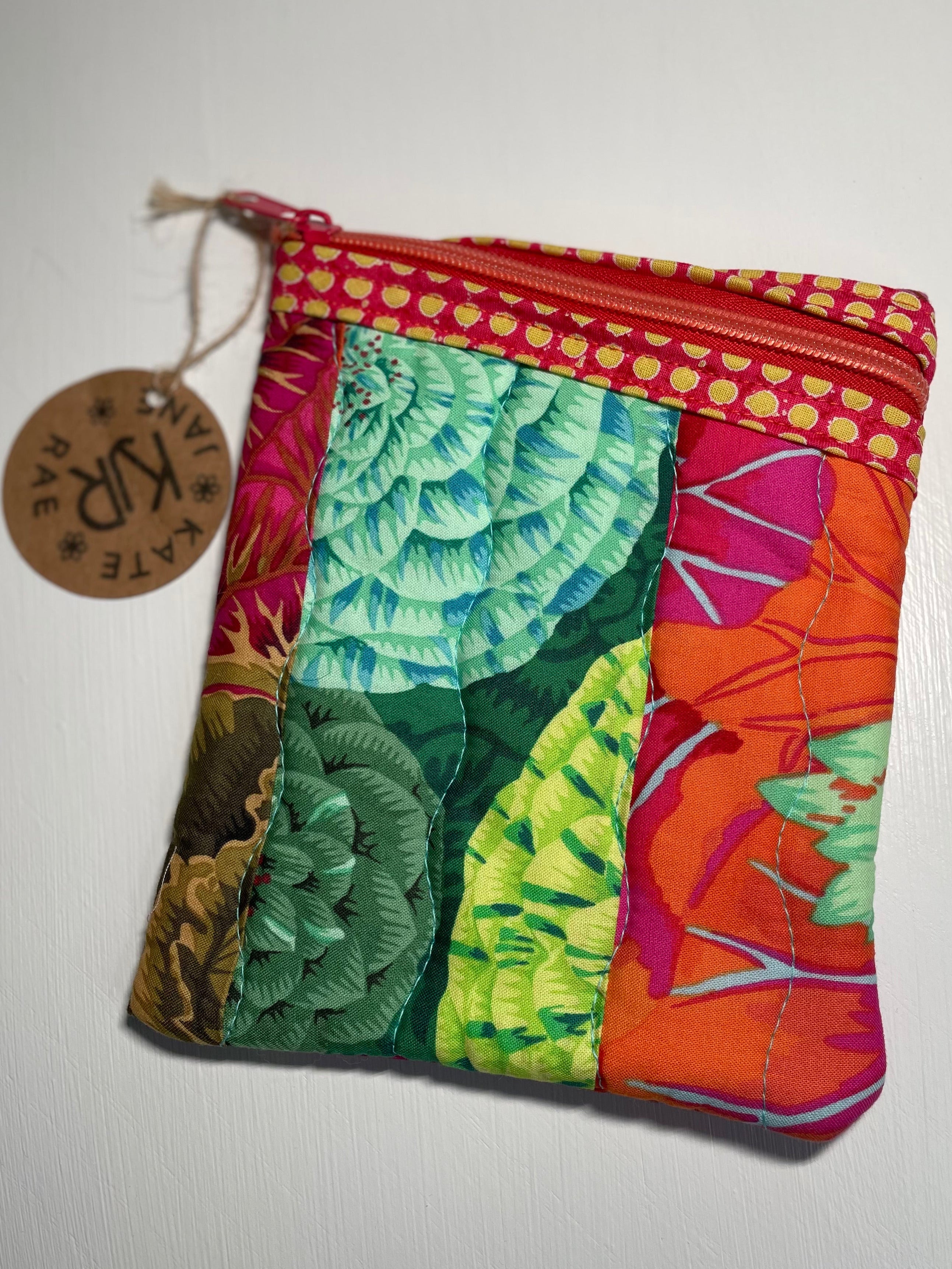 Colorful quilted coin purse with a tag on a light gray background