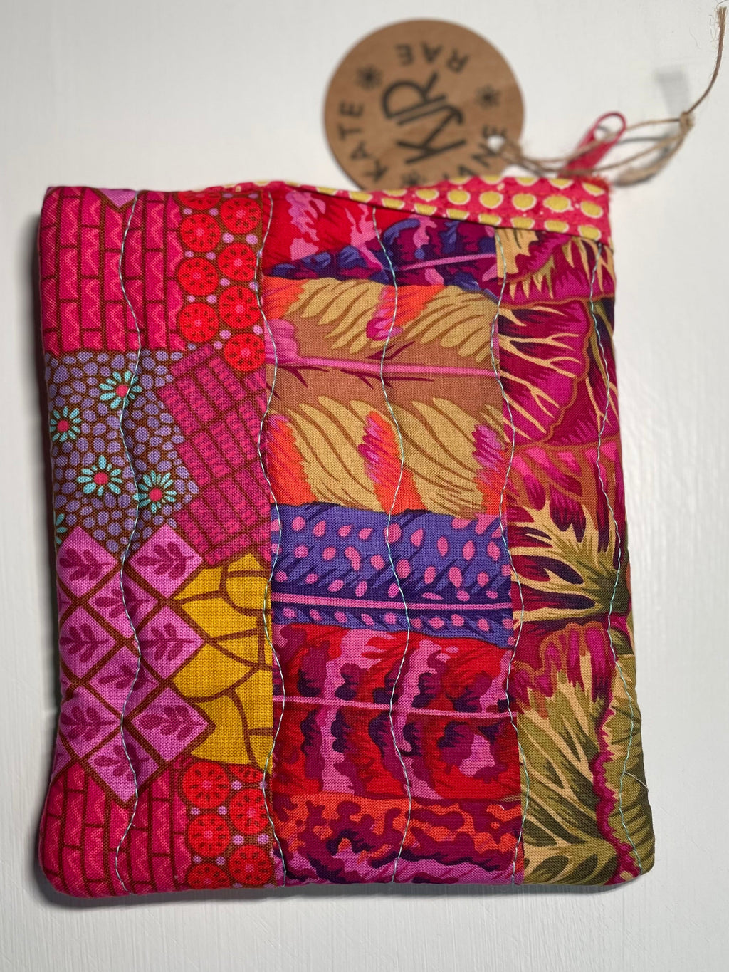 Colorful patchwork pouch with a brand tag on a white background