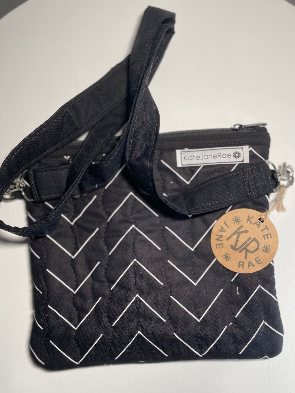 Black quilted bag with a zigzag pattern and visible brand label on a white background