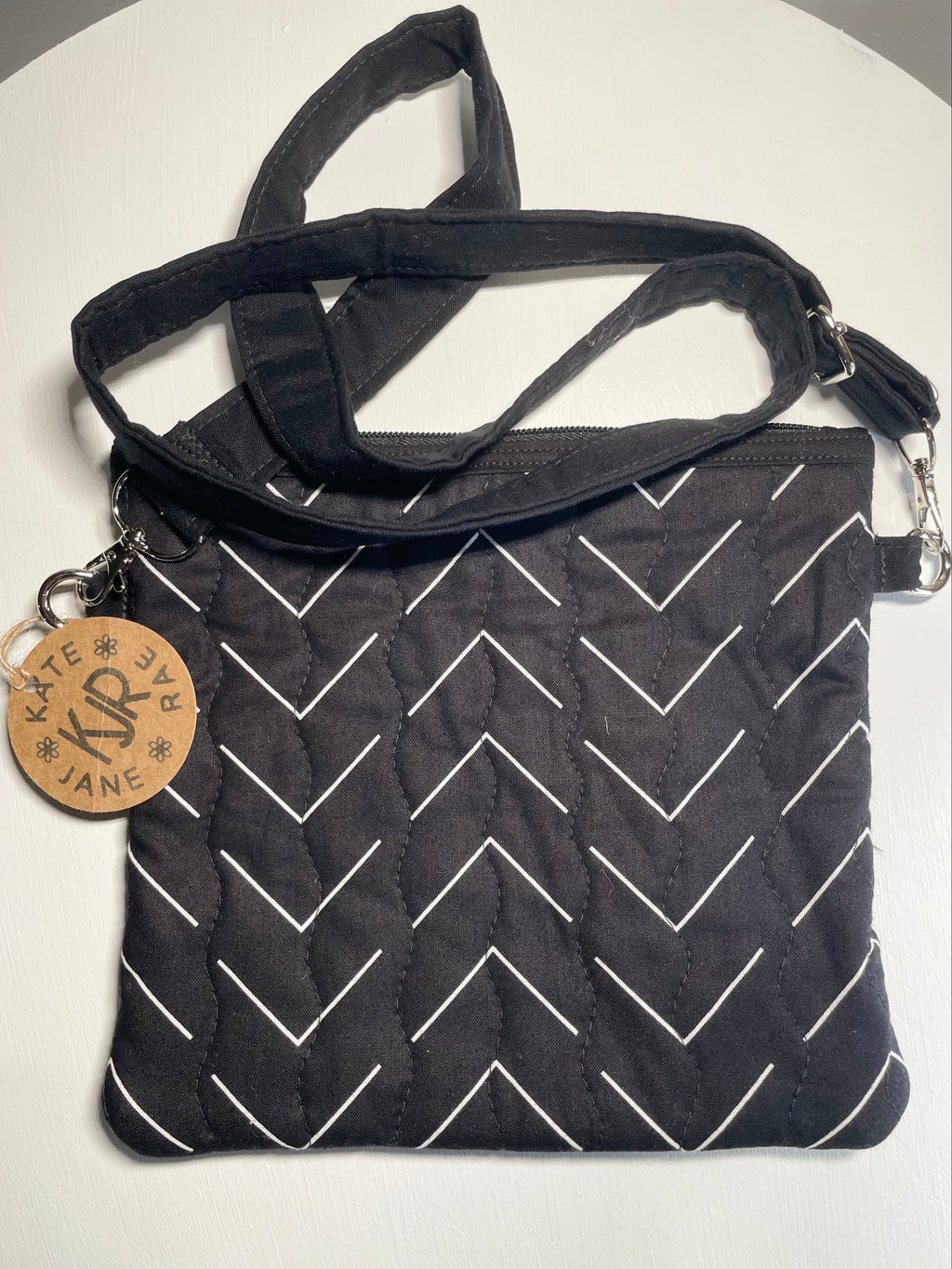 Black bag with white zigzag pattern and a strap on a white background