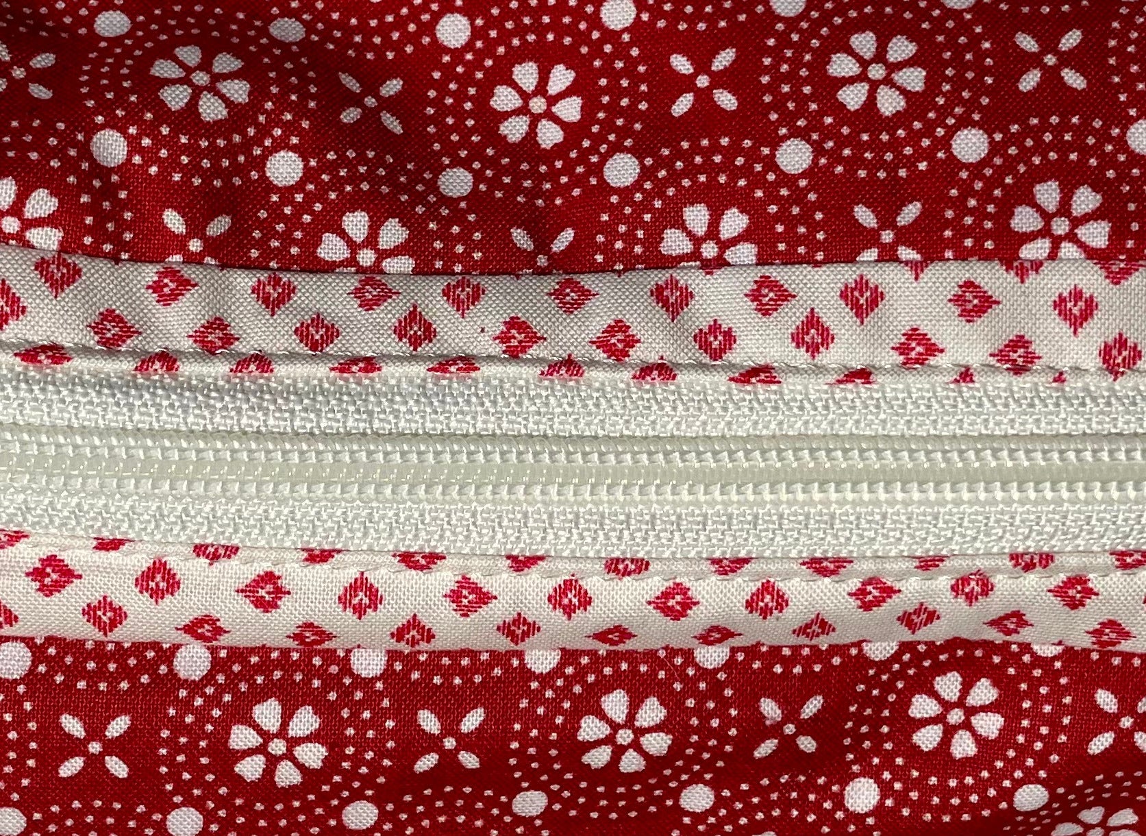 Red and white patterned zippered pouch with a visible brand tag on a white background
