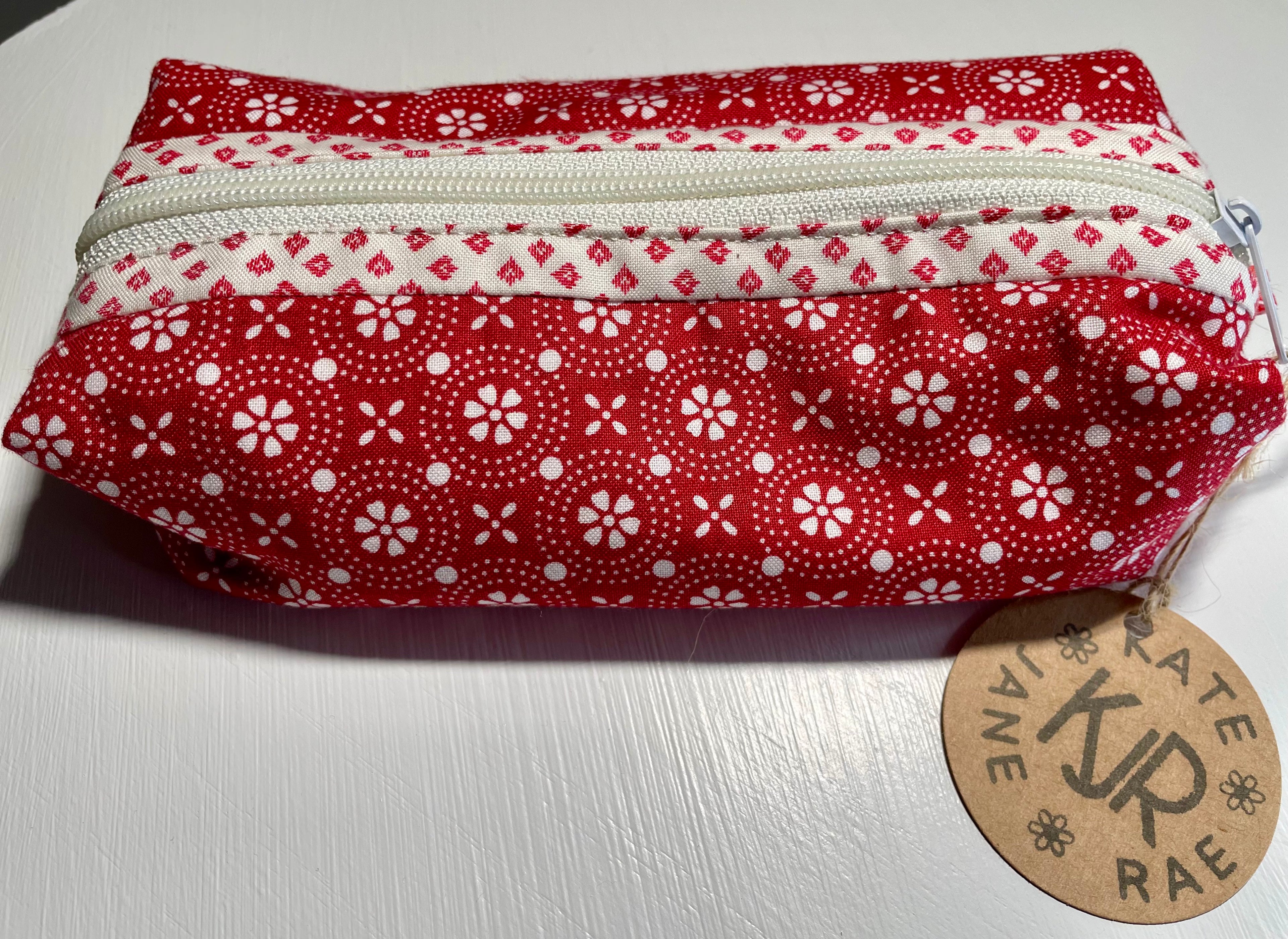 Red and white patterned pouch with a visible brand tag on a light background