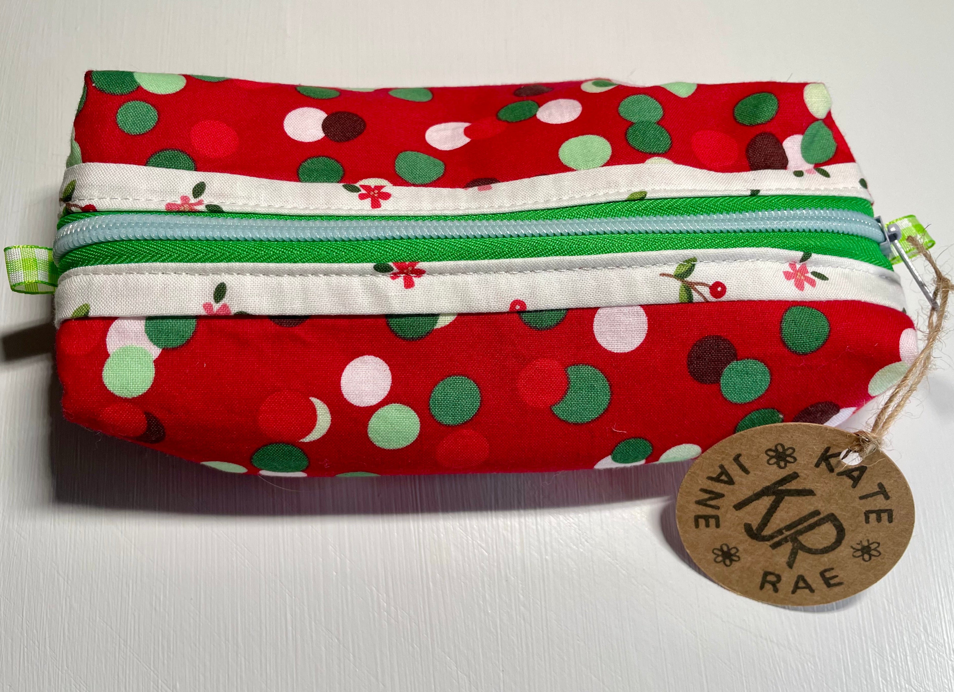 Fabric pouch with polka dot pattern and visible brand tag on a white background